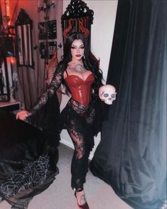 a woman in a red corset and black lace dress holding a skull with her right hand