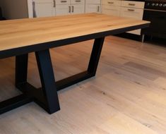 a wooden table sitting on top of a hard wood floor next to white cupboards