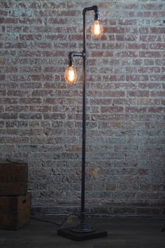 an old fashioned lamp with two bulbs on it in front of a brick wall and wooden boxes