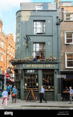 people walking on the sidewalk in front of a building that is called mi fogg's tavern