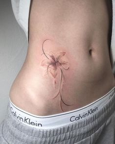 a woman's stomach with a flower tattoo on her belly and the words calvin klein written below it