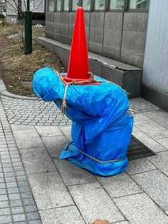 a blue bag with a red cone on it sitting on the ground next to a fire hydrant