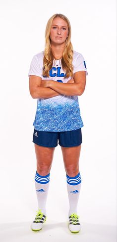 a female soccer player is posing for the camera with her arms crossed in front of her chest