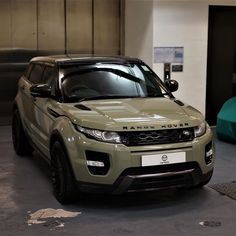 a range rover parked in a garage next to a green car