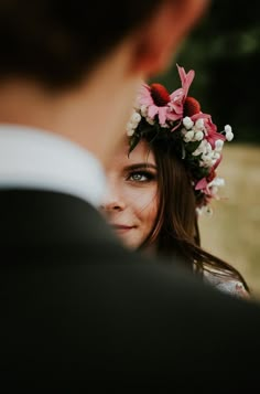 a close up of a person wearing a flower headpiece and looking into the distance