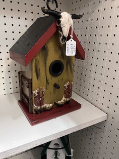 a birdhouse with a cow skull on the roof is sitting on a shelf in a store