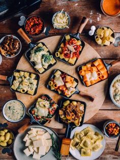 a wooden table topped with lots of different types of food and bowls filled with sauces