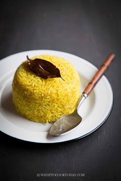 a white plate topped with yellow rice and a spoon