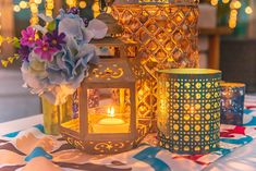 three lit candles sitting on top of a table covered in paper flowers and other decorations