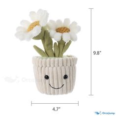 a knitted flower pot with white flowers in it and a smiling face drawn on the side