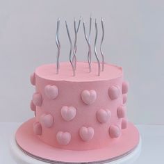 a pink cake with hearts on it and forks sticking out of the icing top