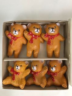 four brown teddy bears in a box with red bows on their heads and chestes