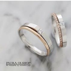 two wedding rings with diamonds on them sitting on a marble countertop in front of a marble background