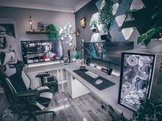 a desk with two monitors and some plants on the wall in front of it,