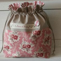 a pink and white flowered bag sitting on top of a wooden table next to a wall