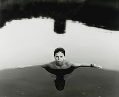 a man swimming in the water with his arms spread out and head tilted to the side