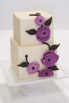 two tiered cake decorated with purple flowers on a white plate in front of a white background