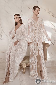 two women in white gowns standing next to each other on a marble flooring