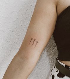 a woman's arm with three small flowers on the back of her left arm