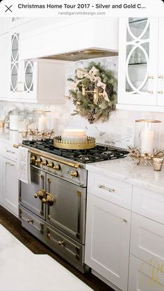 a kitchen decorated for christmas with white cabinets and gold trimmings, an old fashioned stove