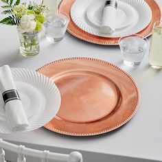 the table is set with plates, silverware and flowers in vases on it