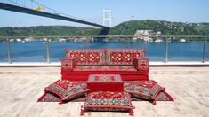 a red couch sitting on top of a wooden floor next to a large body of water