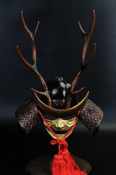 a mask with antlers and horns on it's head is adorned with red tassels