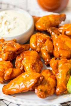 chicken wings and celery on a plate with ranch dressing next to it in a bowl