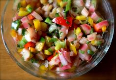 a glass bowl filled with chopped vegetables on top of a wooden table