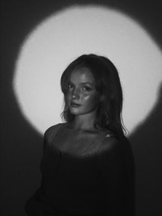 a woman standing in front of a white wall with a shadow on the wall behind her