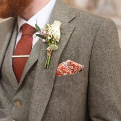 a man wearing a suit and tie with a boutonniere on his lapel