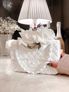 a white purse sitting on top of a table next to a lamp