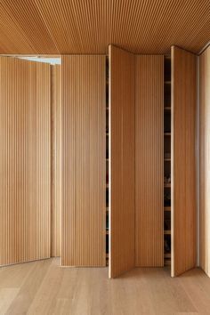 an empty room with wooden slats on the walls and wood flooring in front of it