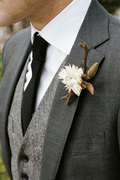 a man wearing a gray suit and white flower boutonniere on his lapel