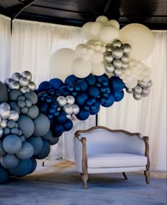 a chair sitting next to a bunch of blue and white balloons hanging from the ceiling