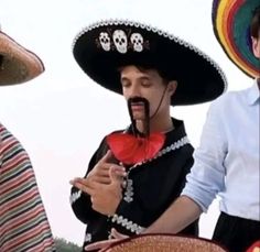 two men wearing sombreros and hats with skulls on them are talking to each other