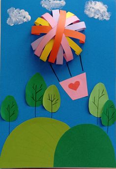 an art project with paper cutouts and trees on the ground, including a hot air balloon