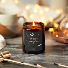 a lit candle sitting on top of a wooden table next to some candles and spoons