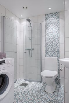 a washer and dryer in a white bathroom with blue patterned tiles on the floor