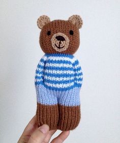 a hand holding a knitted teddy bear in blue and white striped sweater with brown ears