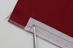 a pair of scissors is laying on the edge of a piece of red fabric next to some thread