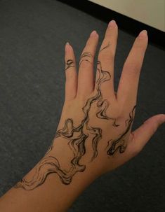 a woman's hand with black ink on it and wavy lines in the middle