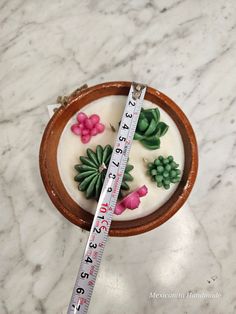 a wooden bowl with flowers on it and a measuring tape