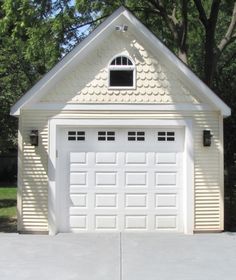 a white garage with two windows on the front and one door open to let in light