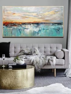 a living room with a couch, coffee table and painting on the wall above it