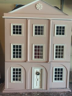 a pink doll house sitting on top of a table next to a white door and window