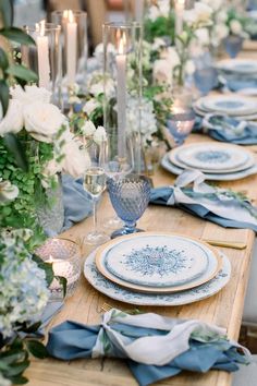 the table is set with blue and white plates, napkins, silverware, and flowers