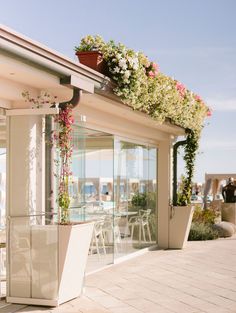 an outdoor restaurant with flowers growing on the roof