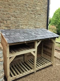 a dog house built into the side of a stone building with a slate roof and wooden slats