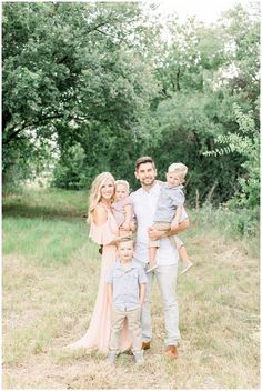 a family posing for a photo in the grass with their two children and one adult